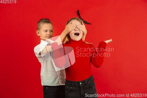 Image of Valentine\'s day celebration, happy caucasian kids isolated on red background