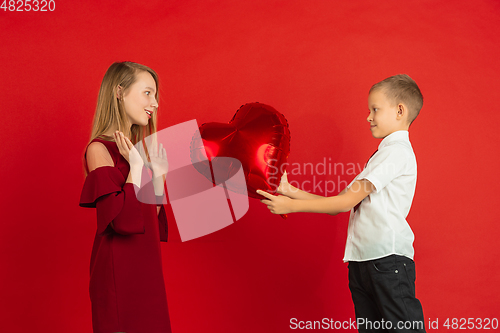 Image of Valentine\'s day celebration, happy caucasian kids isolated on red background