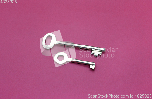 Image of Metal keys close-up on bright crimson paper