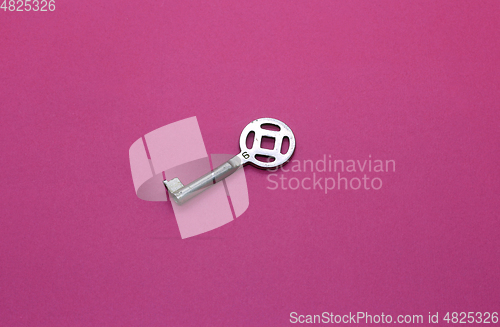 Image of Old metal key on bright crimson paper background