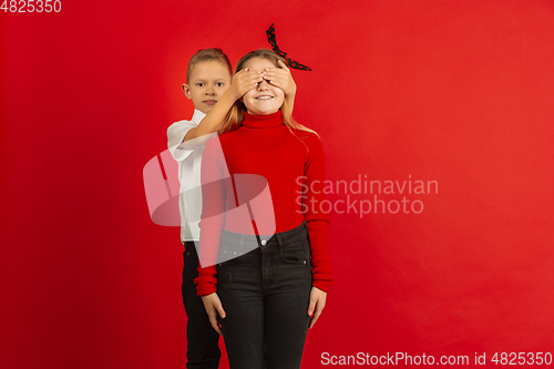 Image of Valentine\'s day celebration, happy caucasian kids isolated on red background