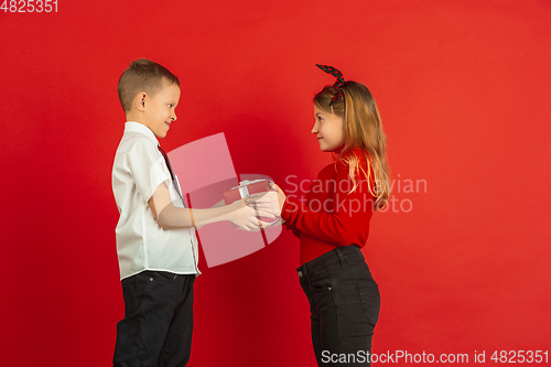 Image of Valentine\'s day celebration, happy caucasian kids isolated on red background