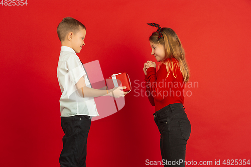 Image of Valentine\'s day celebration, happy caucasian kids isolated on red background