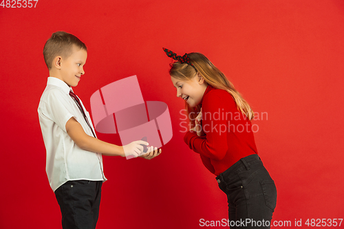 Image of Valentine\'s day celebration, happy caucasian kids isolated on red background