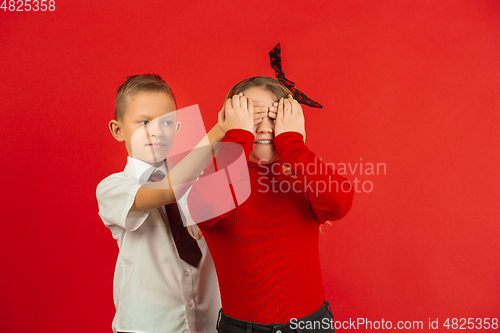 Image of Valentine\'s day celebration, happy caucasian kids isolated on red background