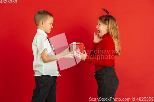 Image of Valentine\'s day celebration, happy caucasian kids isolated on red background