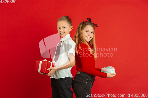 Image of Valentine\'s day celebration, happy caucasian kids isolated on red background