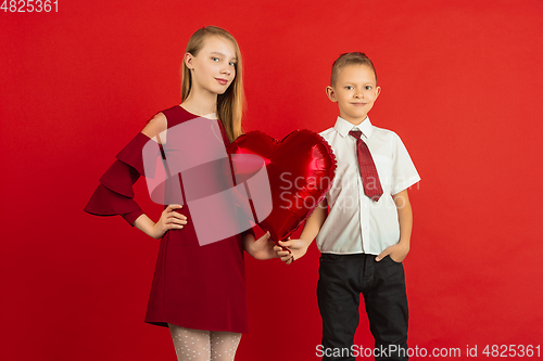 Image of Valentine\'s day celebration, happy caucasian kids isolated on red background