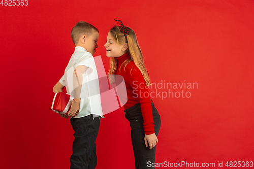 Image of Valentine\'s day celebration, happy caucasian kids isolated on red background