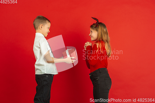 Image of Valentine\'s day celebration, happy caucasian kids isolated on red background