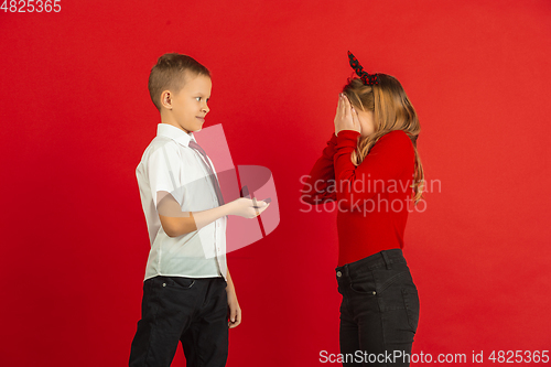 Image of Valentine\'s day celebration, happy caucasian kids isolated on red background