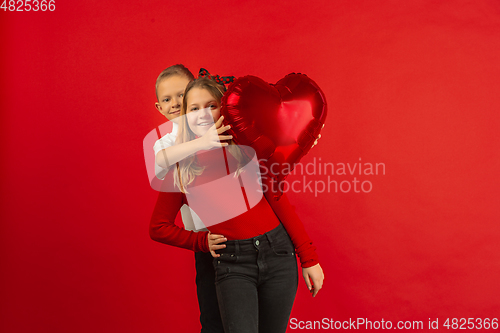 Image of Valentine\'s day celebration, happy caucasian kids isolated on red background