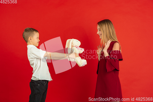 Image of Valentine\'s day celebration, happy caucasian kids isolated on red background