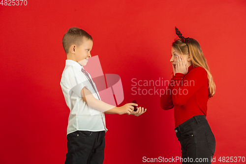 Image of Valentine\'s day celebration, happy caucasian kids isolated on red background