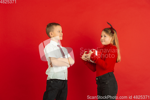 Image of Valentine\'s day celebration, happy caucasian kids isolated on red background