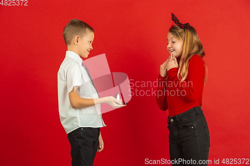 Image of Valentine\'s day celebration, happy caucasian kids isolated on red background