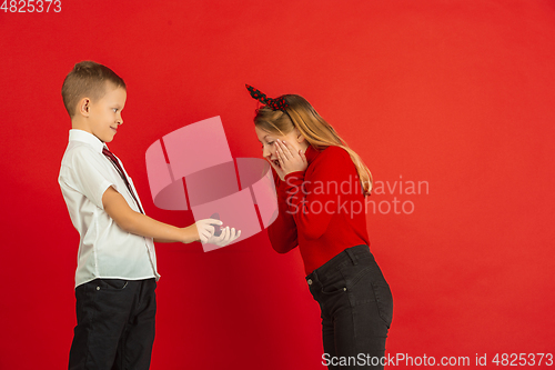 Image of Valentine\'s day celebration, happy caucasian kids isolated on red background