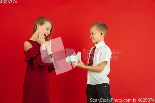 Image of Valentine\'s day celebration, happy caucasian kids isolated on red background