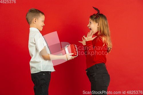 Image of Valentine\'s day celebration, happy caucasian kids isolated on red background