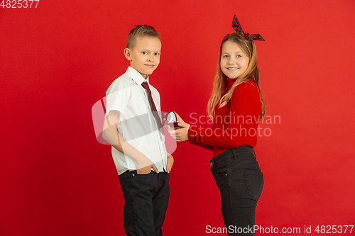 Image of Valentine\'s day celebration, happy caucasian kids isolated on red background