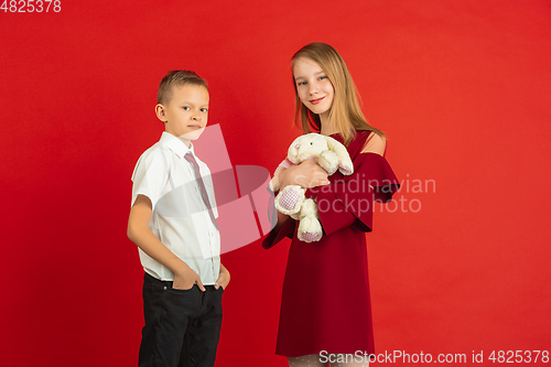 Image of Valentine\'s day celebration, happy caucasian kids isolated on red background