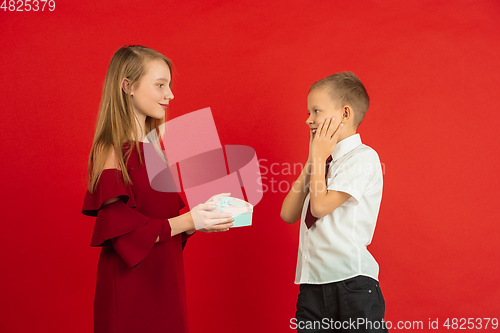 Image of Valentine\'s day celebration, happy caucasian kids isolated on red background