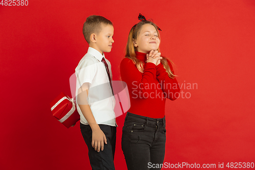 Image of Valentine\'s day celebration, happy caucasian kids isolated on red background