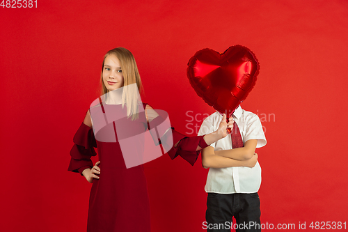 Image of Valentine\'s day celebration, happy caucasian kids isolated on red background