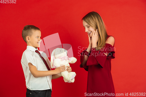 Image of Valentine\'s day celebration, happy caucasian kids isolated on red background