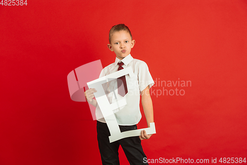 Image of Valentine\'s day celebration, happy caucasian boy holding letter on red background