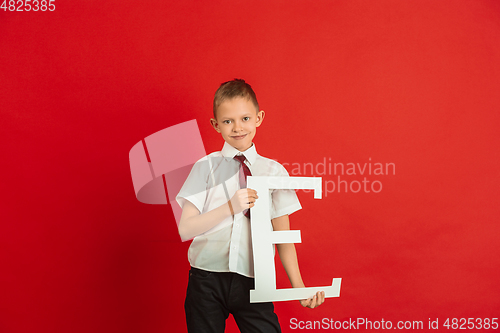 Image of Valentine\'s day celebration, happy caucasian boy holding letter on red background