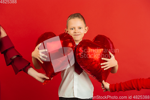 Image of Valentine\'s day celebration, happy caucasian boy isolated on red background