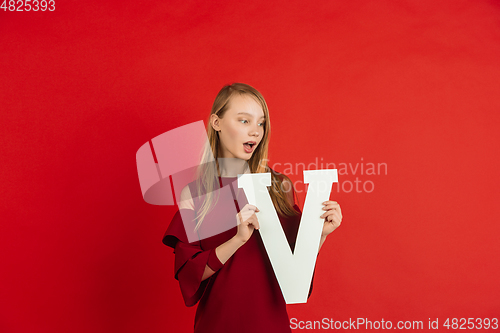 Image of Valentine\'s day celebration, happy caucasian girl holding letter on red background