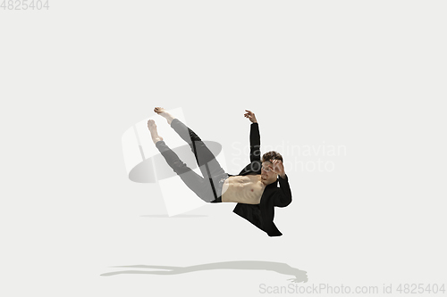 Image of Man in casual style clothes jumping and dancing isolated on white background. Art, motion, action, flexibility, inspiration concept. Flexible caucasian ballet dancer.