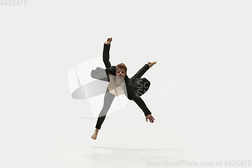 Image of Man in casual style clothes jumping and dancing isolated on white background. Art, motion, action, flexibility, inspiration concept. Flexible caucasian ballet dancer.