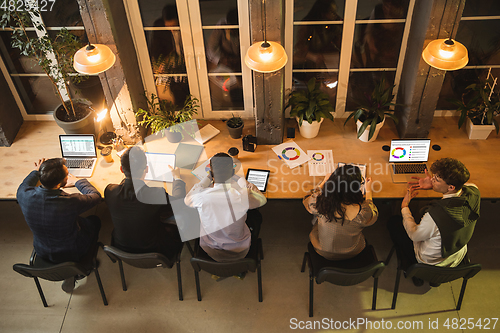 Image of Colleagues working together in modern office using devices and gadgets during creative meeting