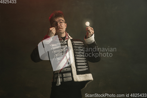 Image of Young man in suit as royal person isolated on dark green background. Retro style, comparison of eras concept. Beautiful male model like historical character, monarch, old-fashioned.