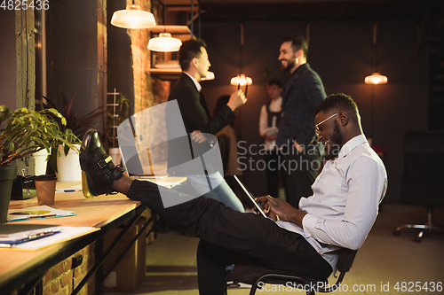 Image of Colleagues working together in modern office using devices and gadgets during creative meeting