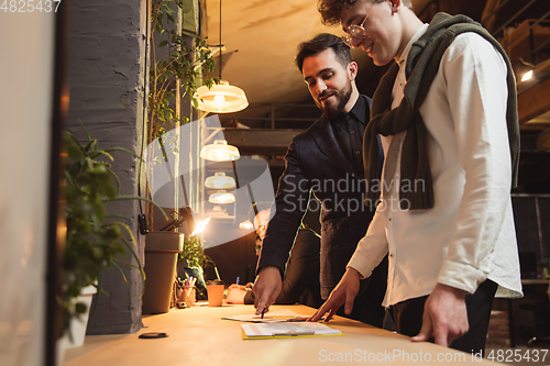 Image of Colleagues working together in modern office using devices and gadgets during creative meeting