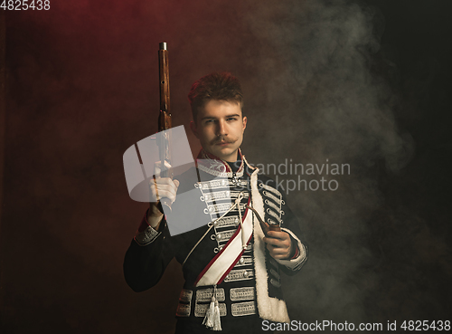 Image of Young man in suit as royal person isolated on dark green background. Retro style, comparison of eras concept. Beautiful male model like historical character, monarch, old-fashioned.