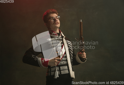 Image of Young man in suit as royal person isolated on dark green background. Retro style, comparison of eras concept. Beautiful male model like historical character, monarch, old-fashioned.