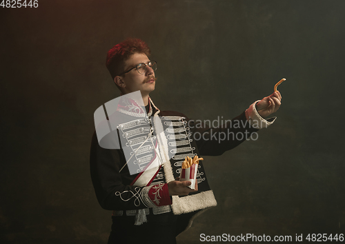 Image of Young man in suit as royal person isolated on dark green background. Retro style, comparison of eras concept. Beautiful male model like historical character, monarch, old-fashioned.