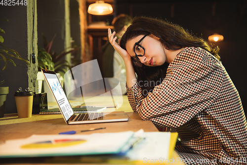 Image of Young woman working together in modern office using devices and gadgets during creative meeting