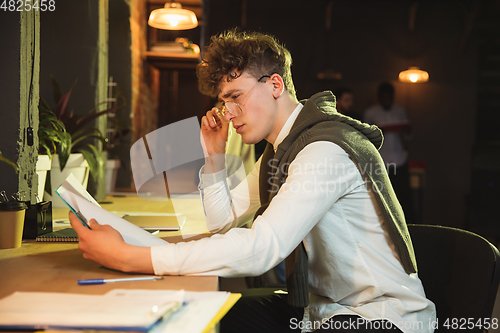 Image of Young man working together in modern office using devices and gadgets during creative meeting