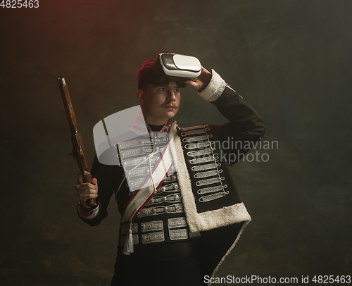 Image of Young man in suit as royal person isolated on dark green background. Retro style, comparison of eras concept. Beautiful male model like historical character, monarch, old-fashioned.