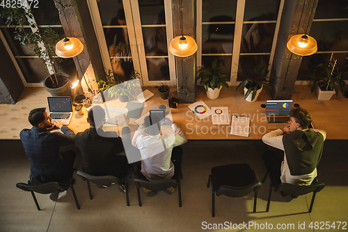 Image of Colleagues working together in modern office using devices and gadgets during creative meeting