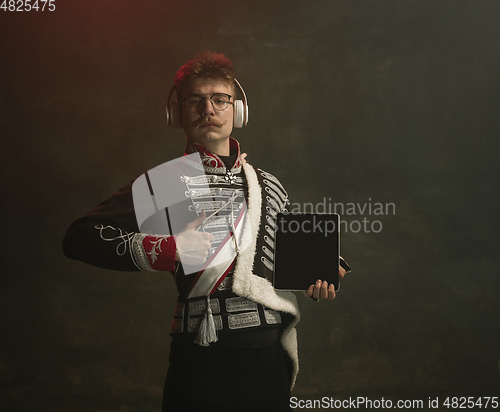 Image of Young man in suit as royal person isolated on dark green background. Retro style, comparison of eras concept. Beautiful male model like historical character, monarch, old-fashioned.