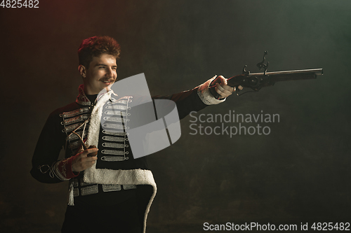 Image of Young man in suit as royal person isolated on dark green background. Retro style, comparison of eras concept. Beautiful male model like historical character, monarch, old-fashioned.