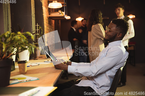 Image of Colleagues working together in modern office using devices and gadgets during creative meeting