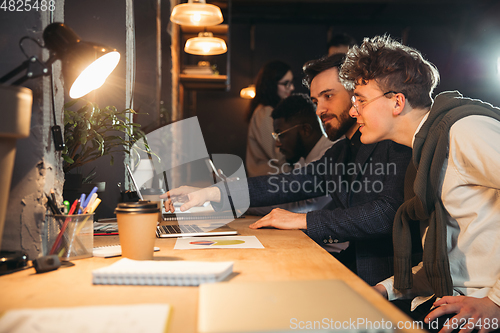 Image of Colleagues working together in modern office using devices and gadgets during creative meeting